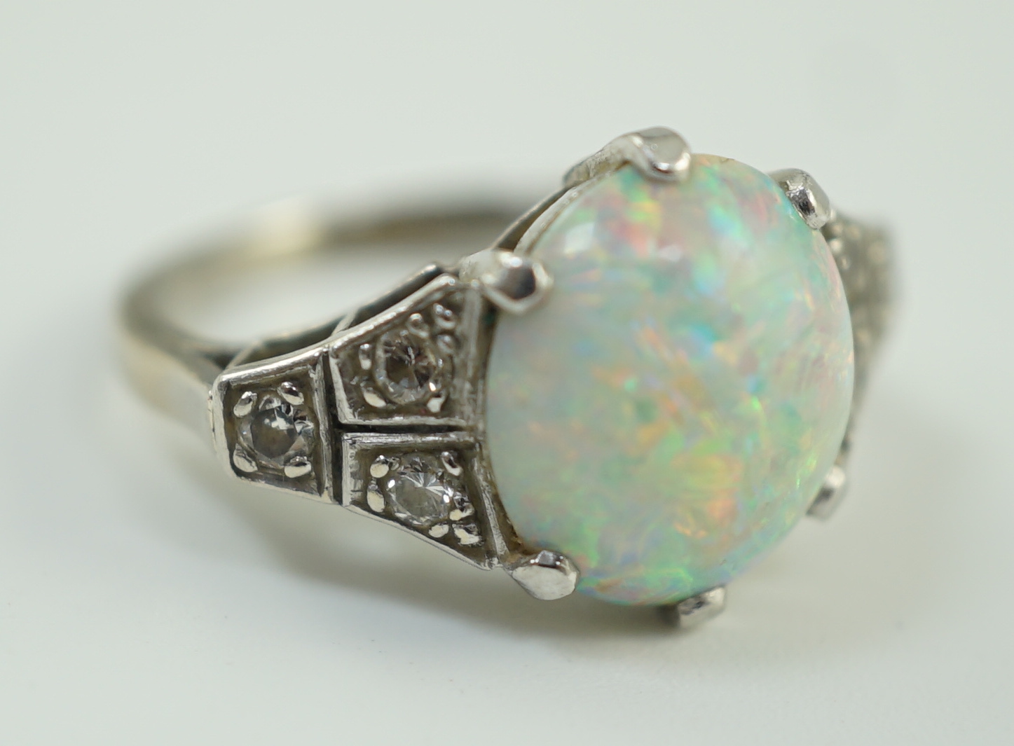 An 18ct white gold, platinum and single stone white opal set dress ring, with six stone diamond set shoulders